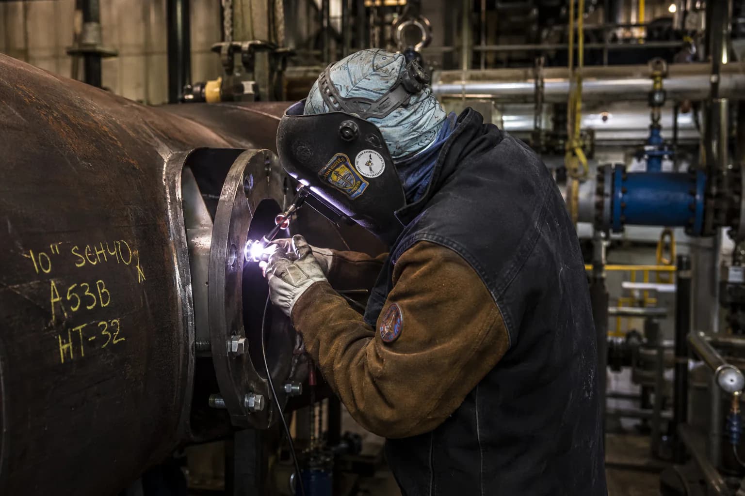 Welder tying in a flange on a large-diameter pipe spool